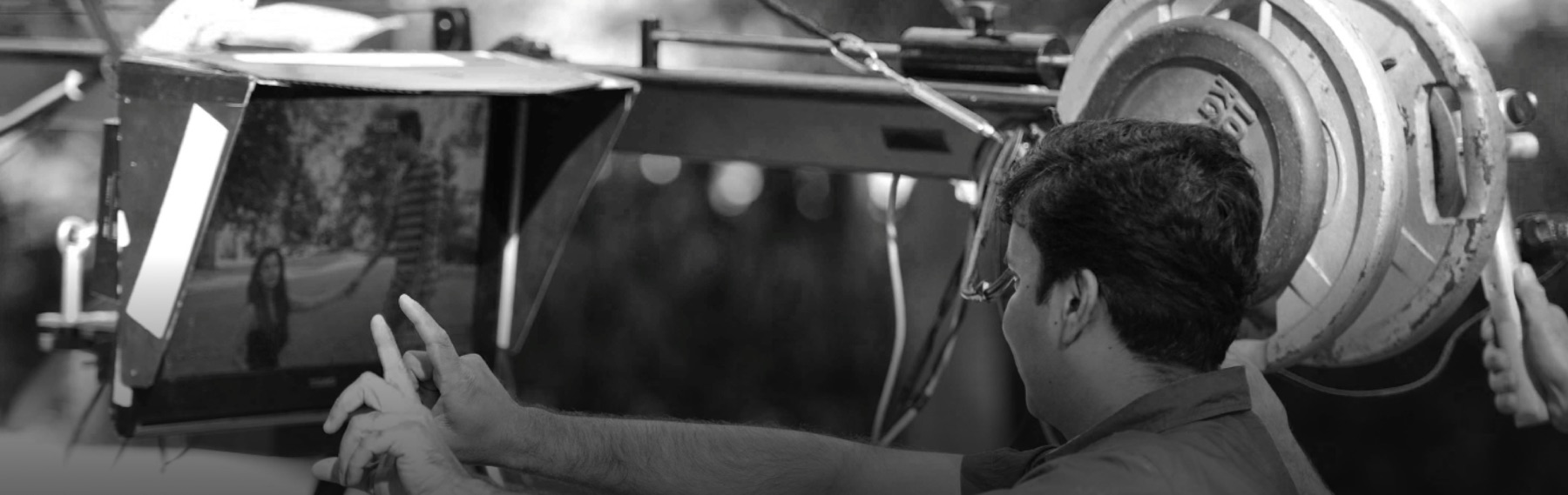 Crew member adjusting a monitor on a film crane, black and white