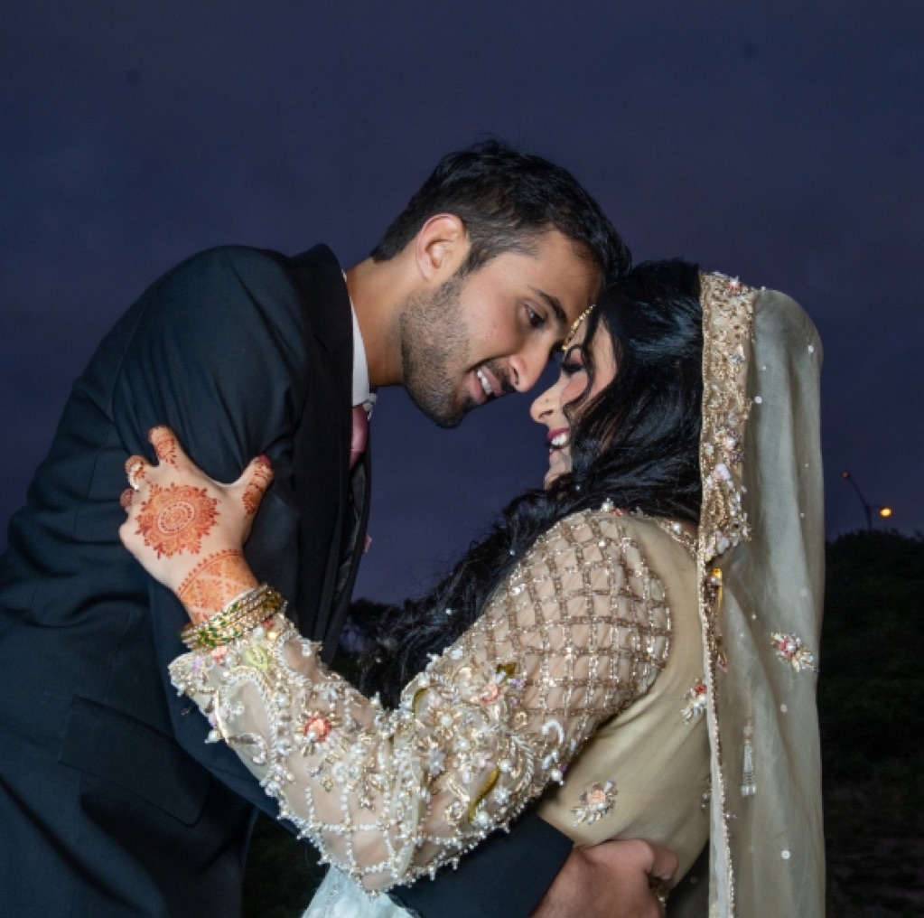 Couple embracing at night, her hands decorated with mehndi