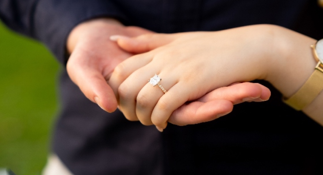 Close-up of joined hands and a diamond engagement ring