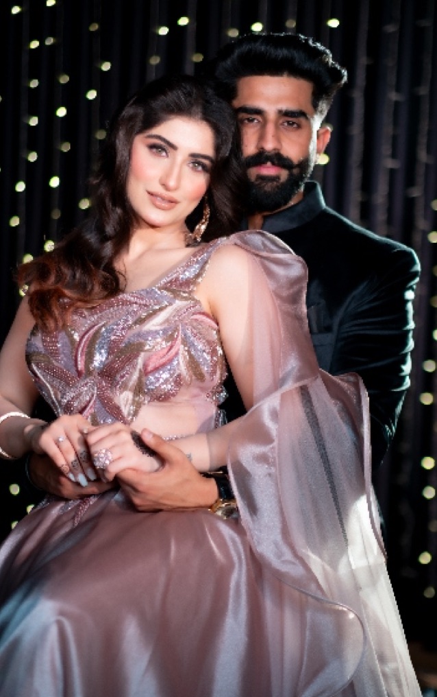 Couple in evening wear in front of a curtain of fairy lights